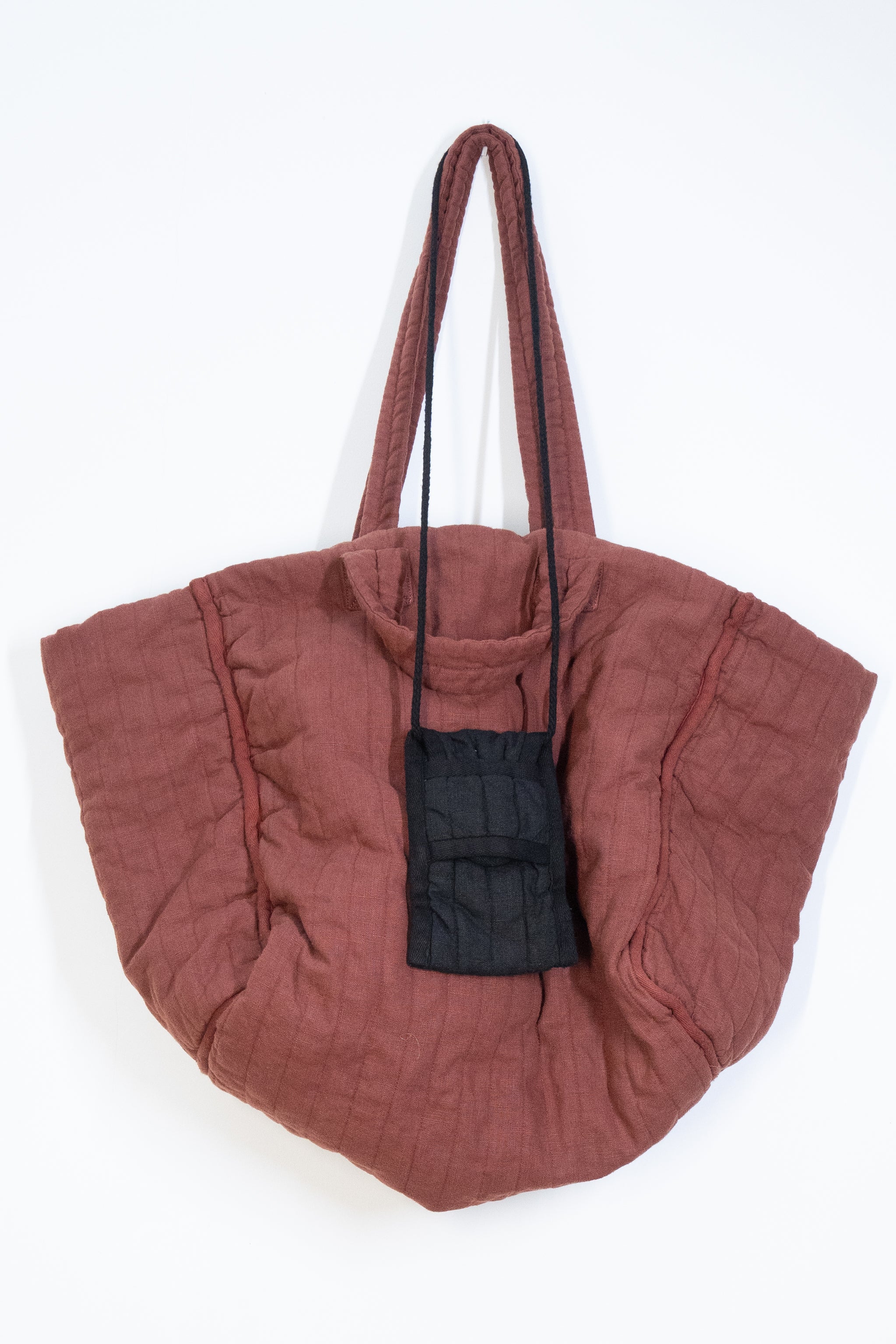 Supersized quilted tote in rosewood linen hung with smaller quilted pocket bag in black linen.  Both from THE REGULAR lifestyle brand